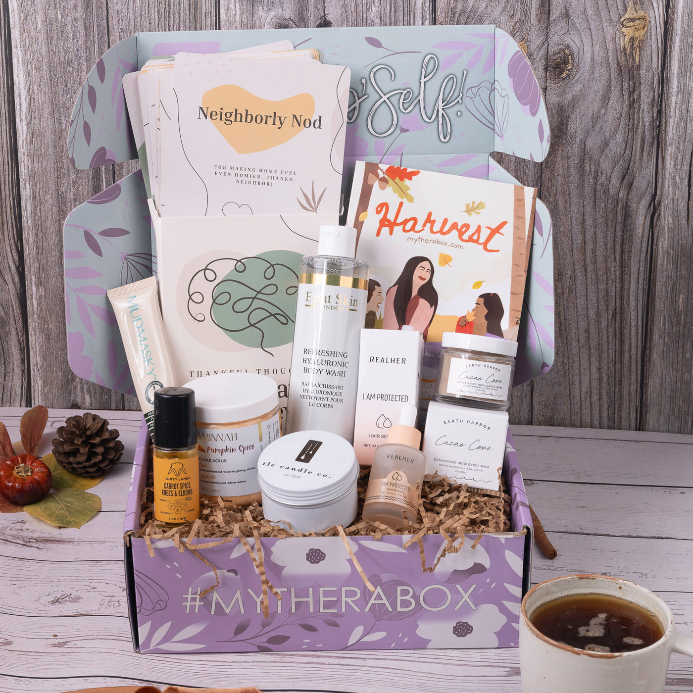 TheraBox Harvest box featuring TLC Candle Co. | Gatherings Candle, Earth Harbor Naturals | Cacao Cove Detoxifying Vitamin C Face Mask, AMINNAH |Pumpkin Spice Sugar Polish, REALHER |I Am Protected Hair Serum, MUDMASKY |Serum-Infused Eye Mask, Eclat Skin London | Refreshing Hyaluronic Body Wash,  Dirty Lamb| Carrot Spice Knees & Elbow, AYNIL | Thankful Thoughts: A 30-Day Journey