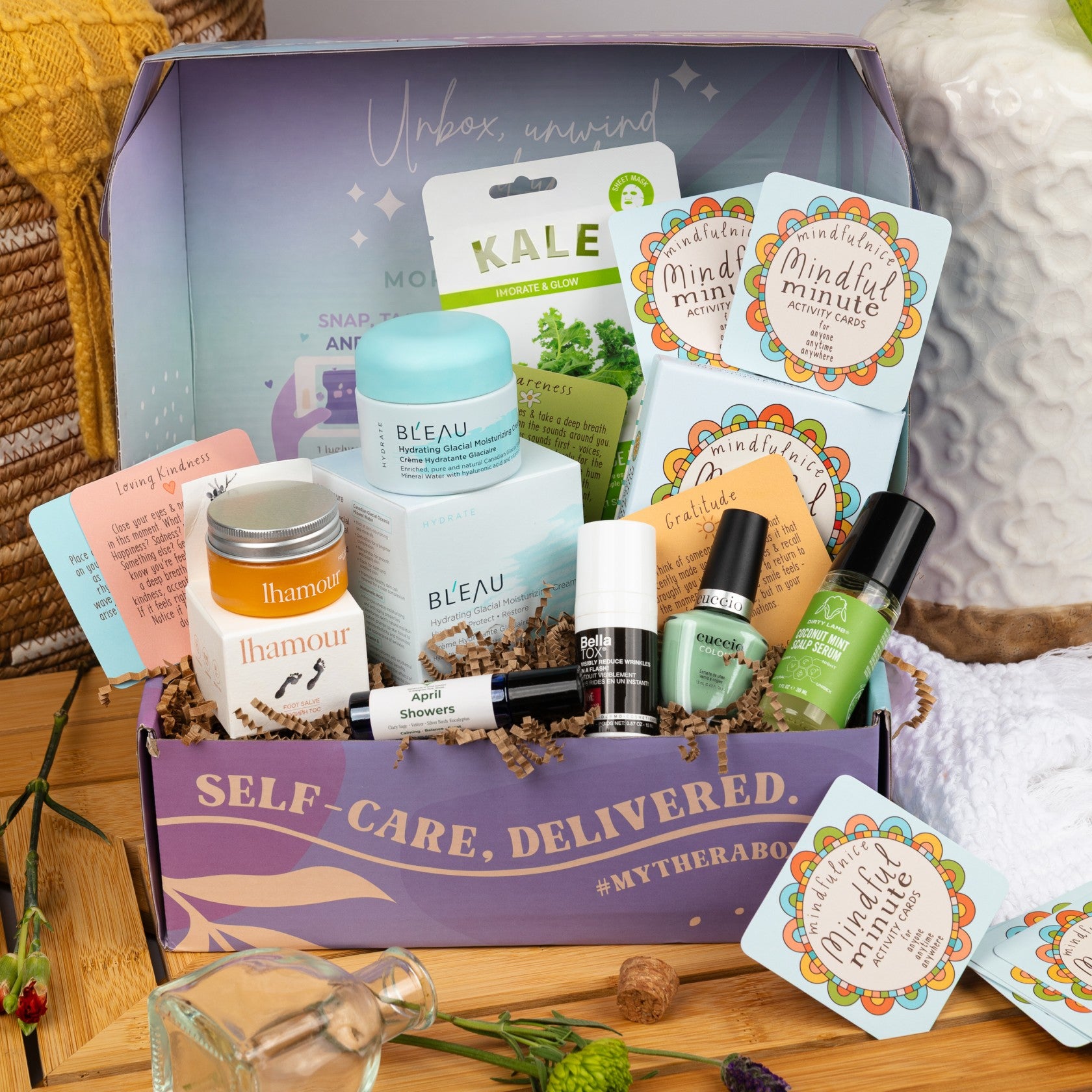 The TheraBox Grounded box features BL’EAU Hydrating Glacial Skincare, THE DIRTY LAMB Coconut Mint Scalp Serum, MORGANNA’S ALCHEMY Bellatox Anti-Aging Serum, NAISTURE Everyday Veggie Slice Mask, BLISSFULLY ROOTED April Showers Aromatic Roller, CUCCIO Paradiso Nail Polish, LHAMOUR Sea Buckthorn Oil Foot Salve, and MINDFULNICE Mindful Minute Activity Cards.