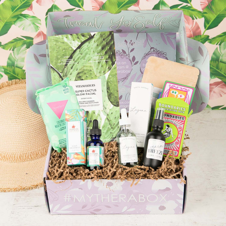 TheraBox Tropics box featuring Tropicgyal Naturals Scalp Treatment, Professional Herb Foot Scrub, Earth Harbor Laguna Body Serum, SweetSpot Labs Coconut Lim Soothing Wipes, Elevation Lifestyle Ocean Breeze Room Spray, Vitamasques Super Cactus Glow Facial, Microcosm Publishing Boundaries Deck